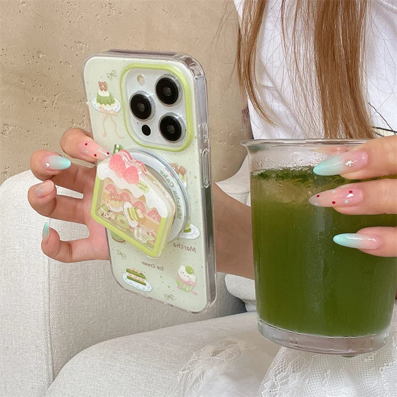 Kawaii Matcha Cake Phone Grip, this is the set that has the case and grip, a woman is holding it with an iced matcha drink in the other hand.