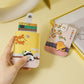 Two cartoon-themed card holders on a yellow surface with a hand holding one of them.