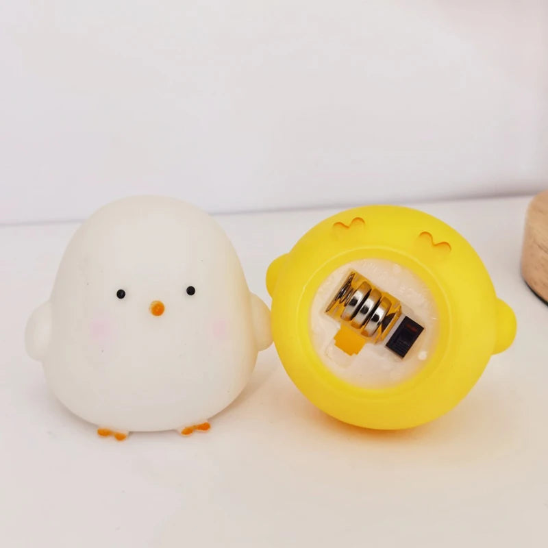 A small white chick-shaped object with a black eye, pink cheek, and orange beak stands beside a yellow chick-shaped container showing a gold-toned lock inside.