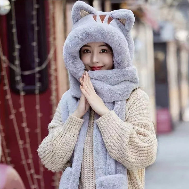 Person wearing a kawaii gray cat-themed hat and scarf on a blurred street background