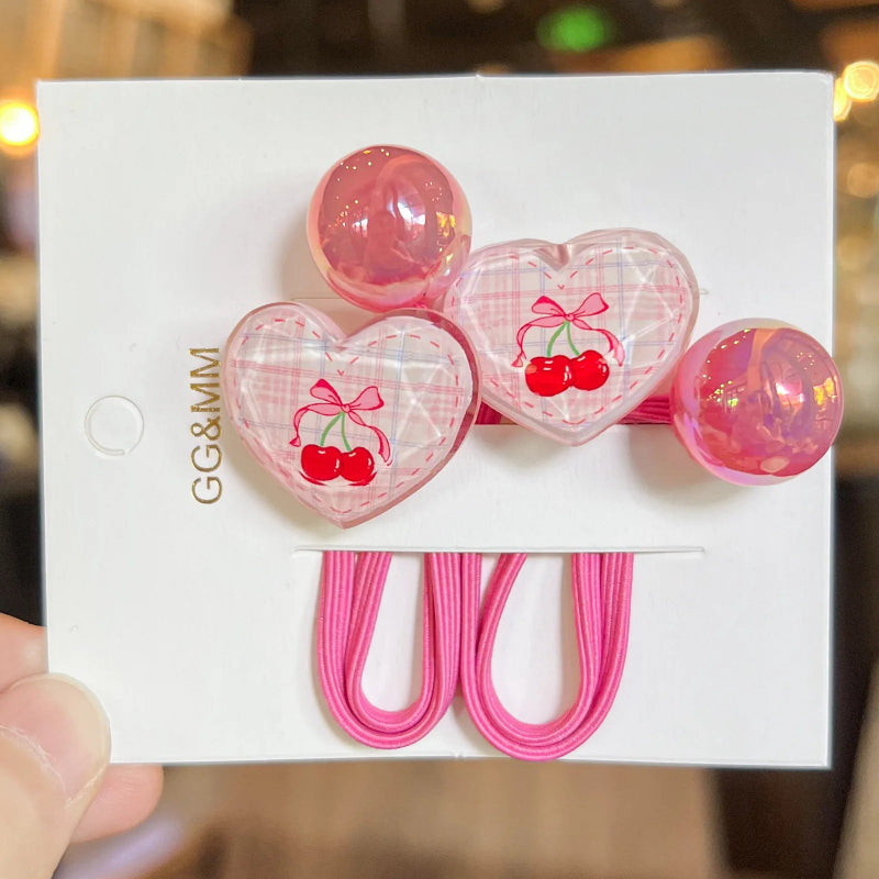 Heart-shaped hair clips with cherry design on a white card, held by a hand.