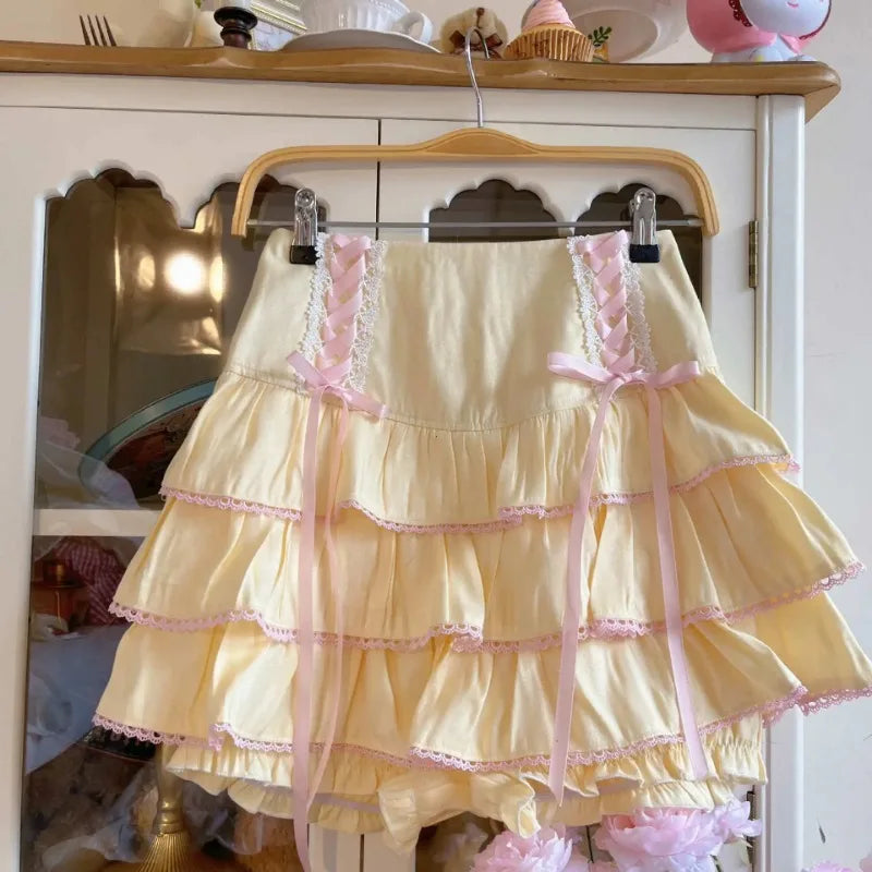 Yellow ruffled skirt with pink trim on a hanger against a white cabinet background.
