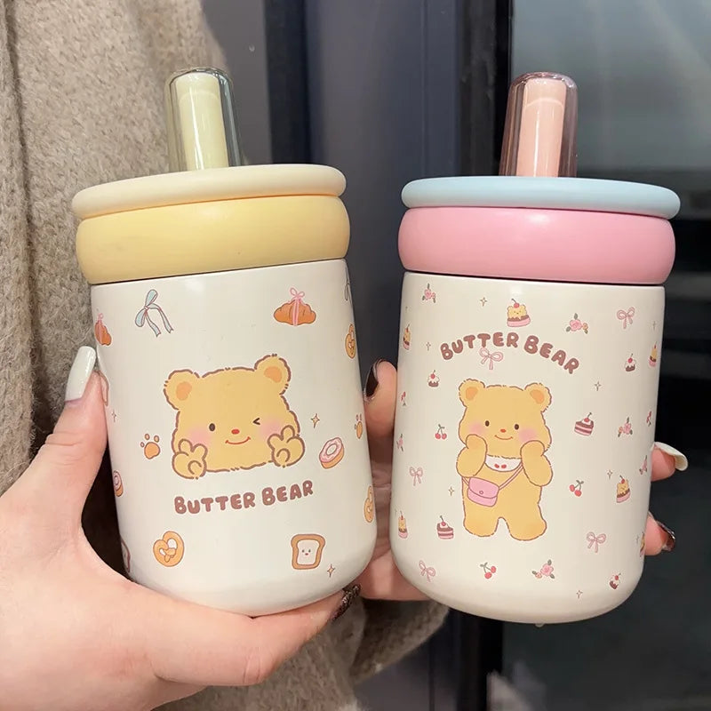 Two kawaii bear-themed cups with colorful lids held by a person.