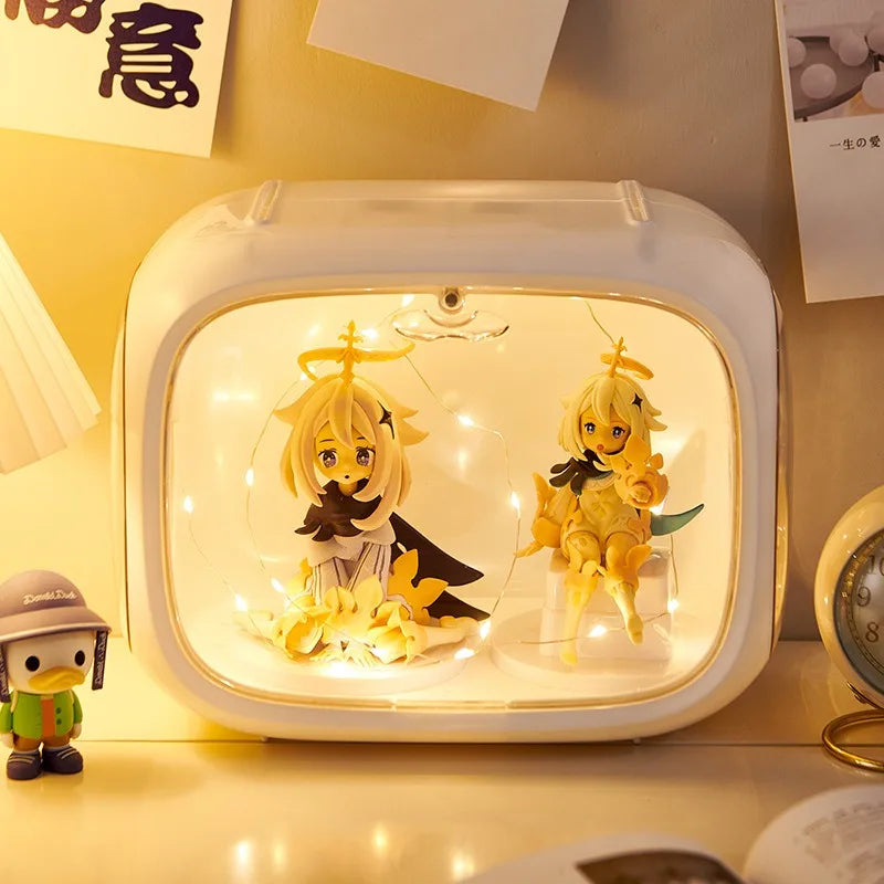 A white rectangular light box with rounded corners, filled with warm white fairy lights and two anime-style blonde character figures, placed on a tabletop with a small duck figurine nearby.