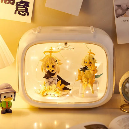 A white rectangular light box with rounded corners, filled with warm white fairy lights and two anime-style blonde character figures, placed on a tabletop with a small duck figurine nearby.