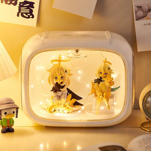 A white rectangular light box with rounded corners, filled with warm white fairy lights and two anime-style blonde character figures, placed on a tabletop with a small duck figurine nearby.