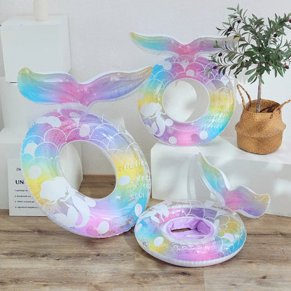 Colorful inflatable mermaid tail on a wooden surface with a plant and books in the background.