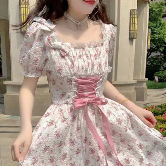 Woman wearing a floral dress with a pink ribbon in an outdoor setting
