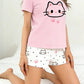 Person wearing a pink t-shirt with a cat design and white shorts with cat patterns on a white background