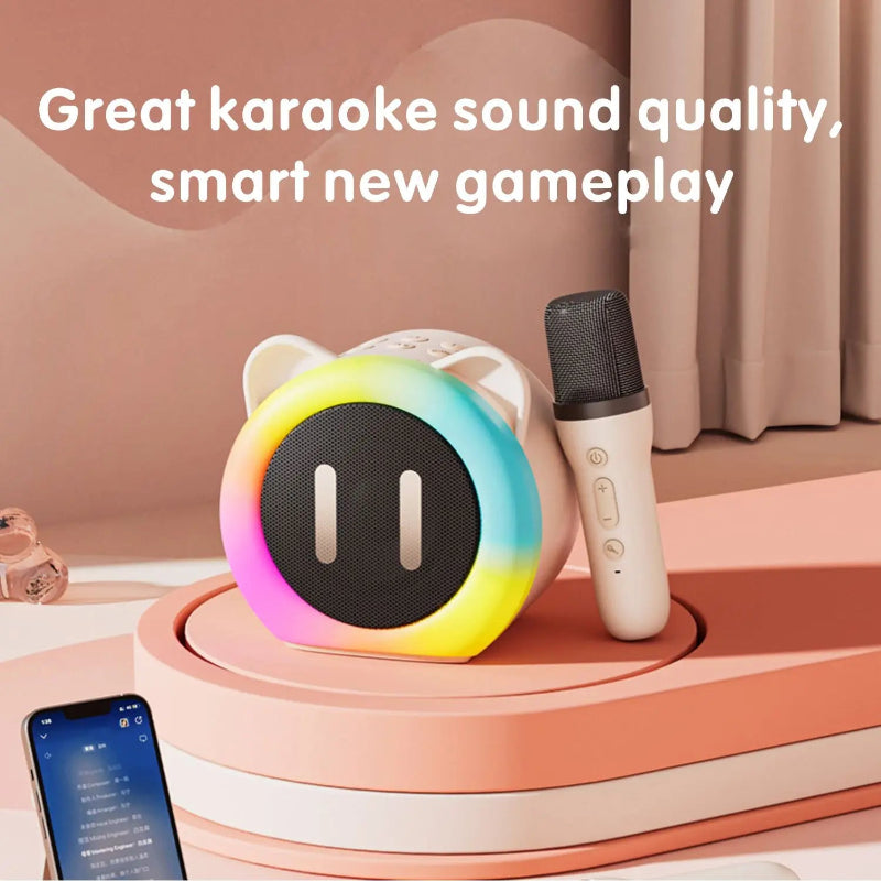 Cute Cat Mini Karaoke Speaker pink edition displayed on a pink table top with a microphone and phone next to it.