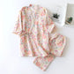 Floral pajama set on a white surface with a small plant and book in the background.