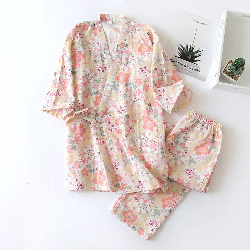 Floral pajama set on a white surface with a small plant and book in the background.