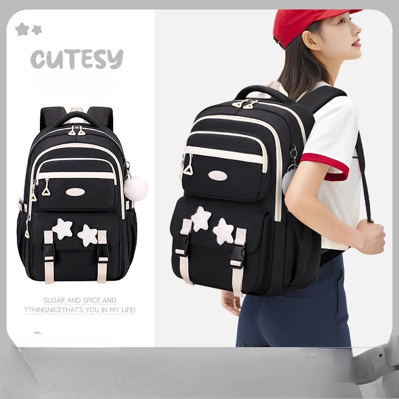 Black backpack with white stars worn by a person, displayed on a gray background.