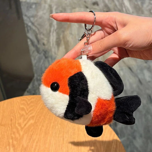 Plush koi fish keychain held by a hand against a neutral background
