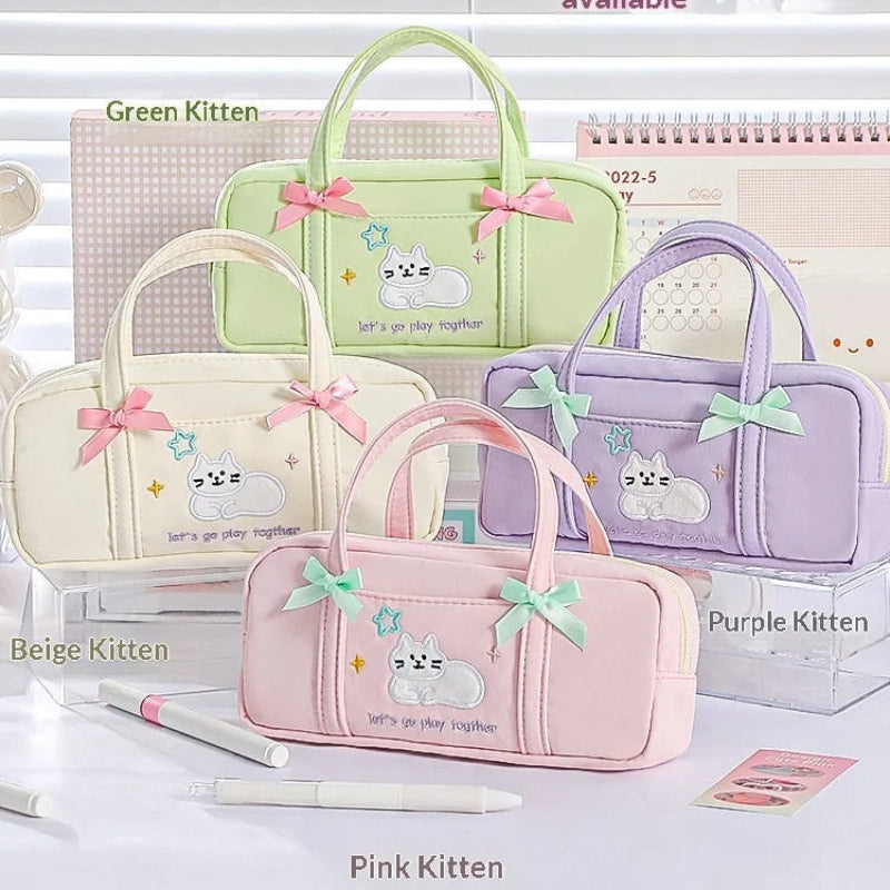 Set of four pastel-colored pencil bags with cat designs and bows on a white surface.