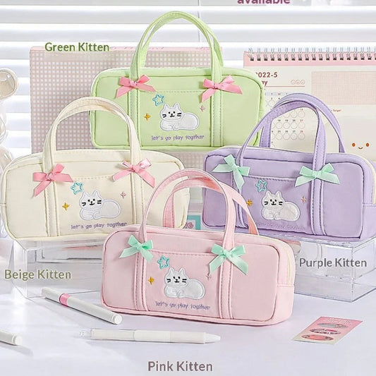 Set of four pastel-colored pencil bags with cat designs and bows on a white surface.