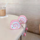 Pink swiss roll shaped air pod case with a blurred indoor background