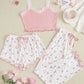 Pink lace top and floral pajama set on a beige surface with pink flowers and a cup.