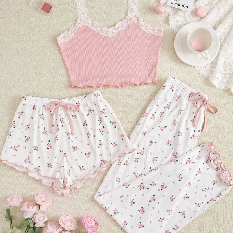 Pink lace top and floral pajama set on a beige surface with pink flowers and a cup.