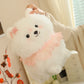 White pomeranian plush toy with pink accents held by a person indoors