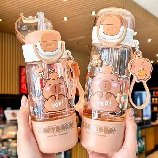 Two cute capybara themed water bottles held in hands with a blurred indoor background.