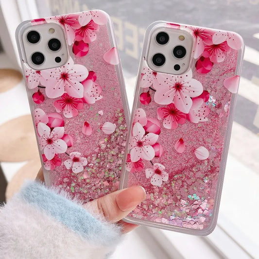Two phone cases with pink cherry blossom design held by a person.