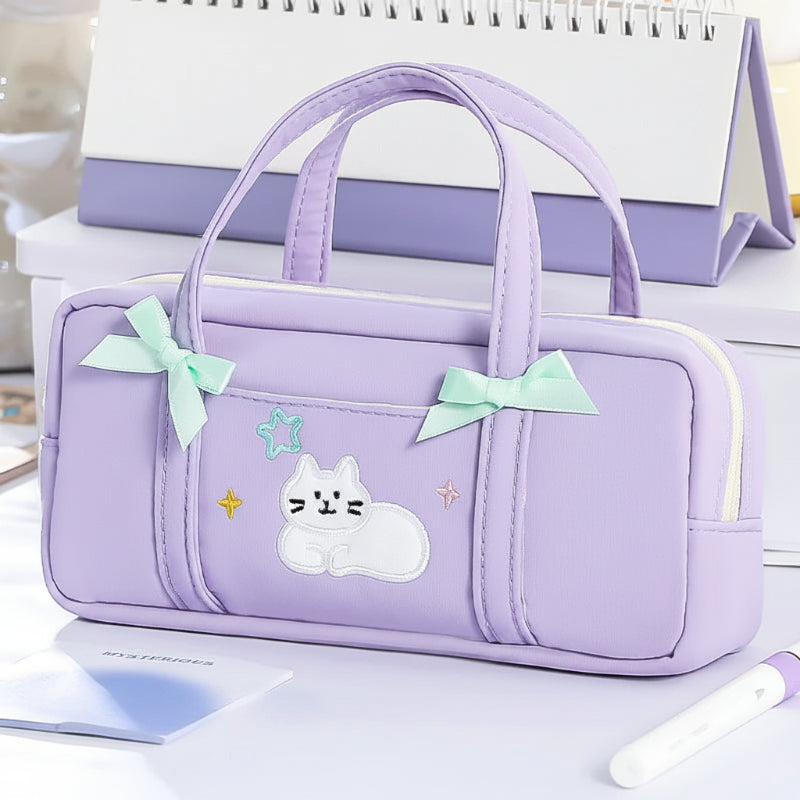 Purple pencil bag with cat design and green bows on a reflective surface.