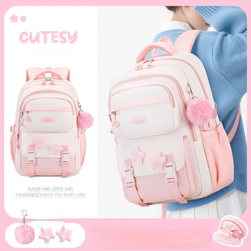 Cutesy pink backpack with star and pom-pom details, worn by a person.