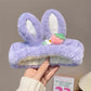 Purple kawaii bunny headbands with white ears held by a hand against a neutral background