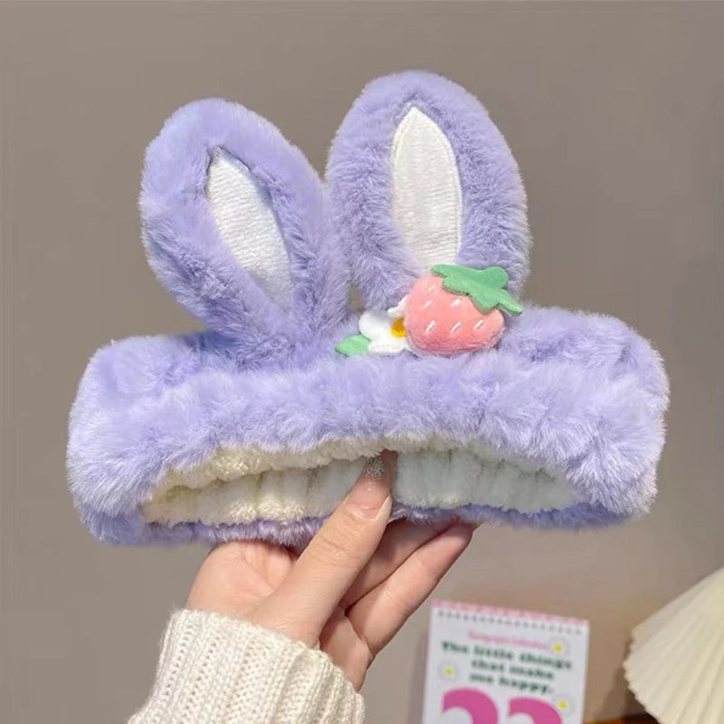 Purple kawaii bunny headbands with white ears held by a hand against a neutral background