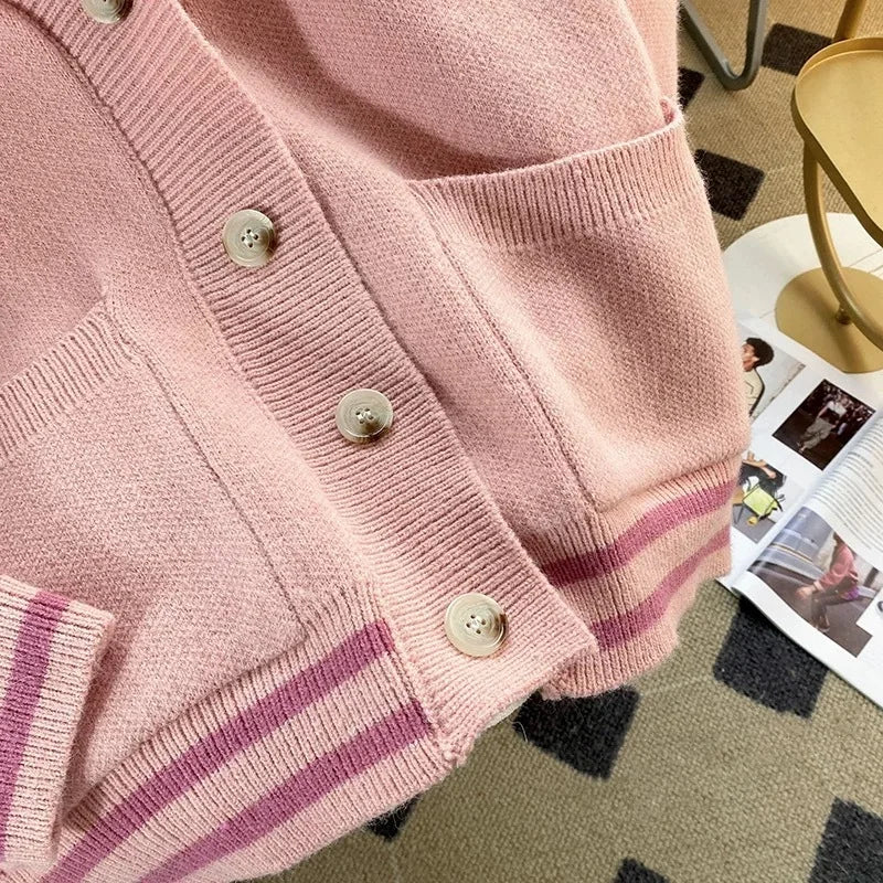 Sweet Teddy Bear Cardigan pastel pink edition with a bear sown into the chest area whilst the sleeves have large black stitches where they have been joined and black strips on the wrist cuffs and black and pink trim, this image is displaying the buttons and the lower trim design.