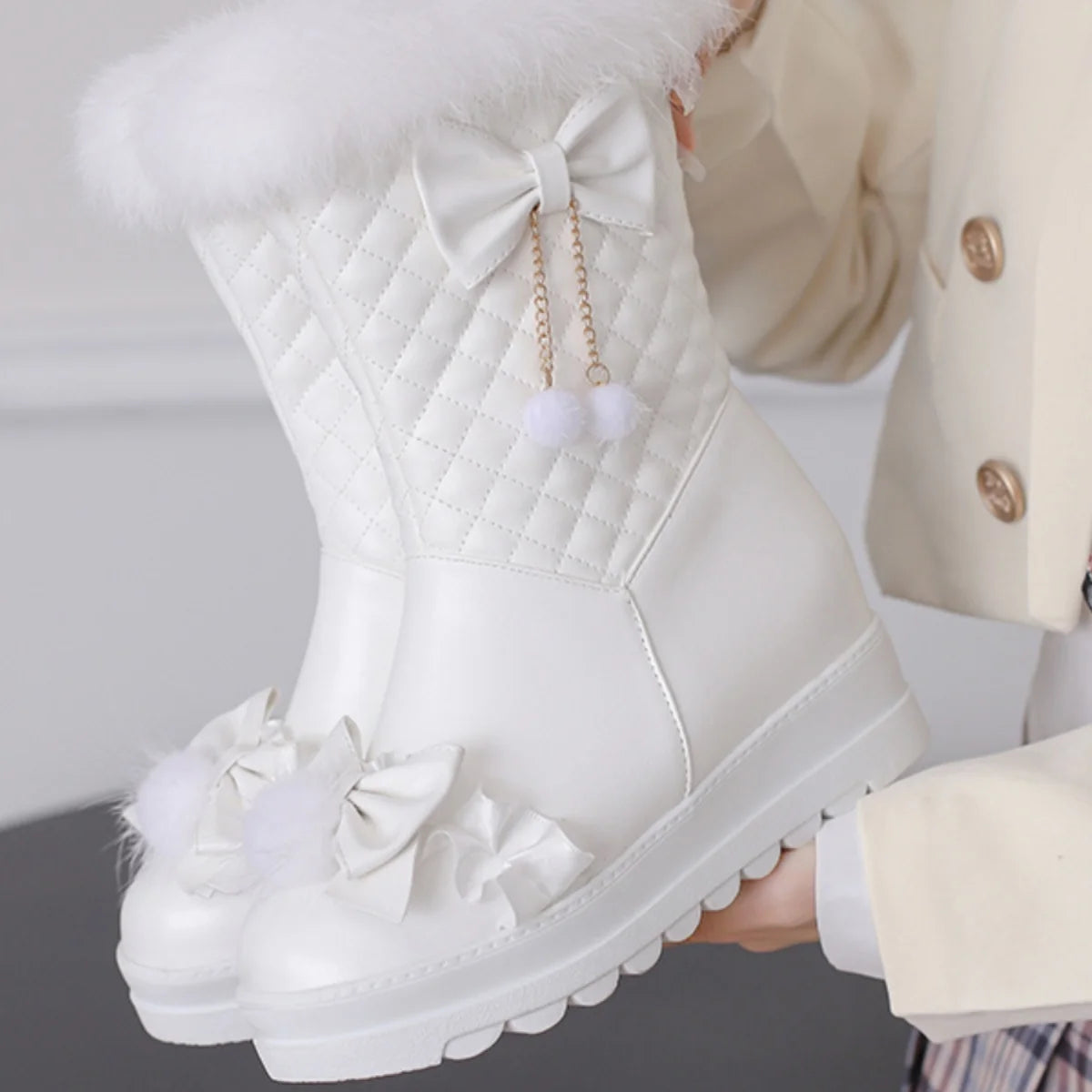 White winter boot with decorative elements held by a person wearing a beige coat.