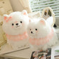 Two fluffy white pomeranian plush toys with pink collars on a table.