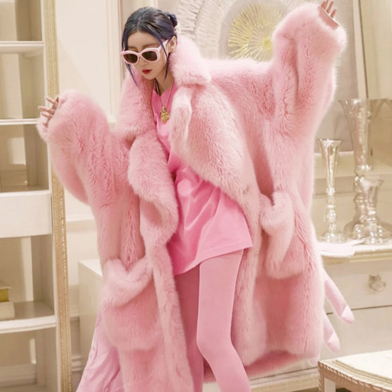 A woman modeling a voluminous light pink faux fur coat over a matching pink outfit, standing in an ornate indoor room. The brand name 'Lautaro' is visible in the top left corner.