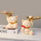 Two decorative cat figurines with trays on a neutral background