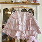 Pink ruffled dress on a hanger against a white cabinet background