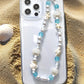 Mermaid treasure phone charm bracelet displayed on sandy beach