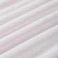Close-up of textured white fabric with a subtle pattern on a light pink background