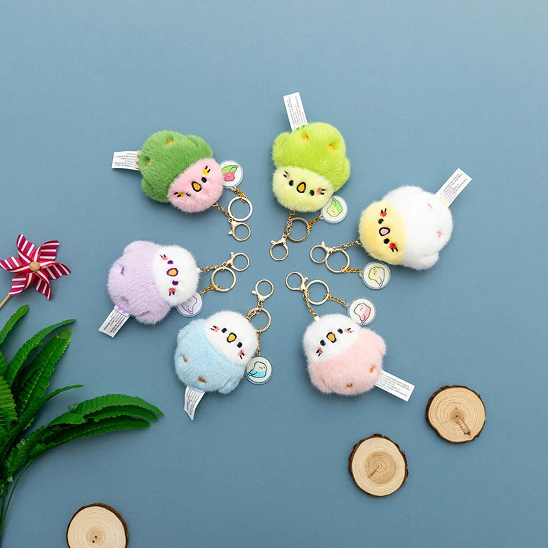 Set of colorful bird plushie pendant  keychains on a blue background with decorative elements.