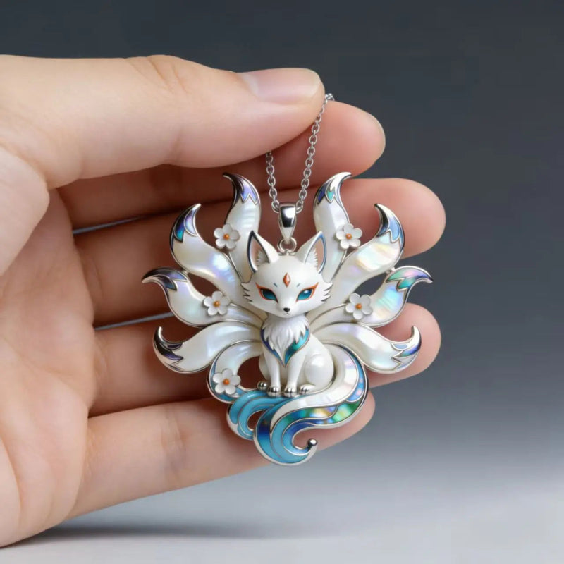Silver Kitsune pendant with floral details held in a hand against a dark background