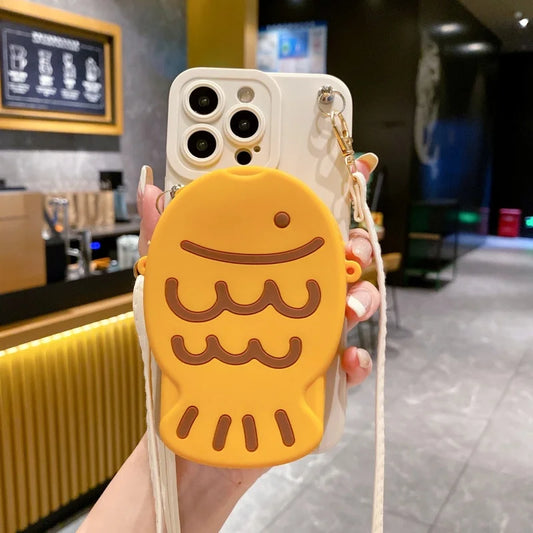 Phone case with Taiyaki design held in a hand, blurred background of a cafe.