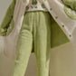 A person wearing a plush fleece pajama set in light green, including matching pants and a button-front cardigan with a white sherpa lining and small printed motifs.