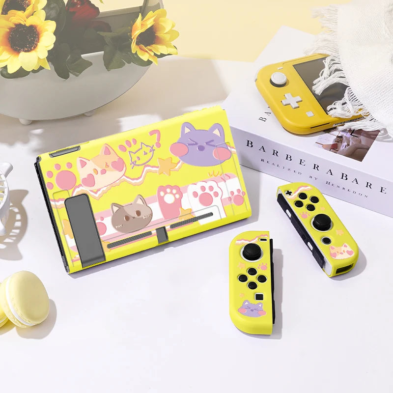 Yellow gaming console with cat-themed design on a white surface with a magazine and flowers in the background.