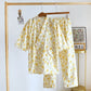 Floral pajama set hanging on a wooden rack against a white wall.