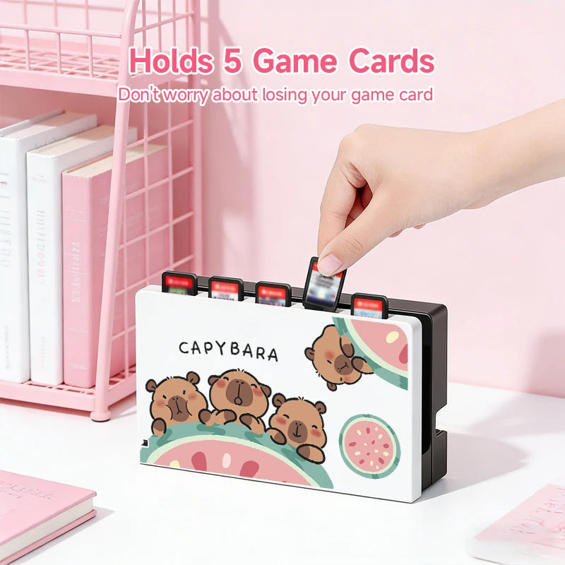 kawaii capybara watermelon switch case the white design which is now displaying the dock case that comes with it having the same capybara design as the switch case holding game cards, on a white desk.