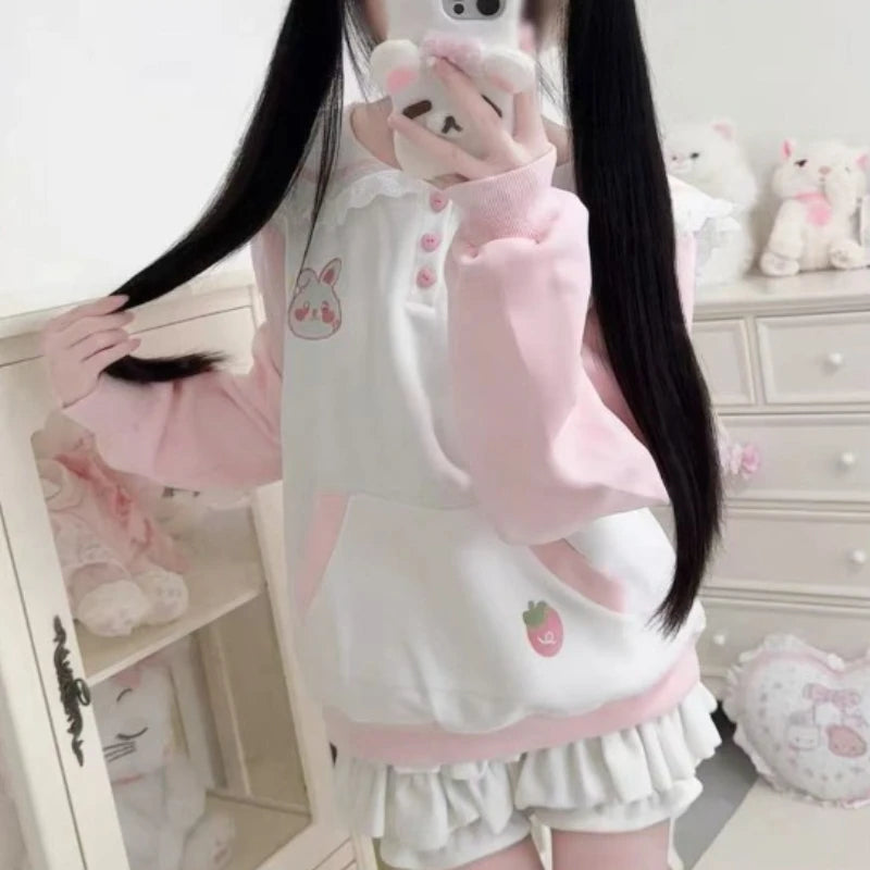 Person wearing a pink and white outfit with kawaii designs in a room.
