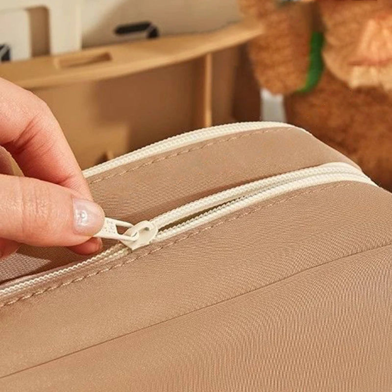 Hand zipping a beige bag with a blurred background