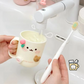 Person holding a kawaii mug with a face, pouring water into it, and a toothbrush next to it on a white background.