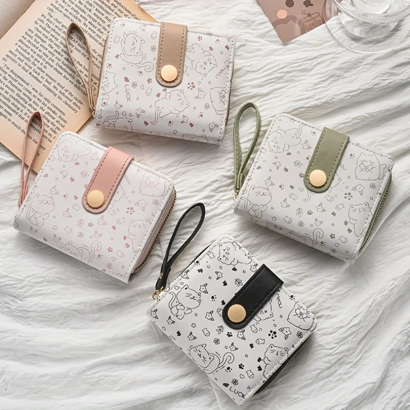 Four small cat patterned wallets on a textured surface