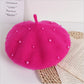 Hot Pink beret with pearl embellishments on a white surface with text and wicker mat.